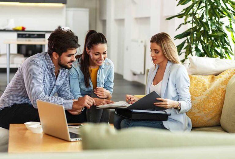 A homeowner reviews an insurance policy beside jewelry receipts, home inventory papers, and a laptop.